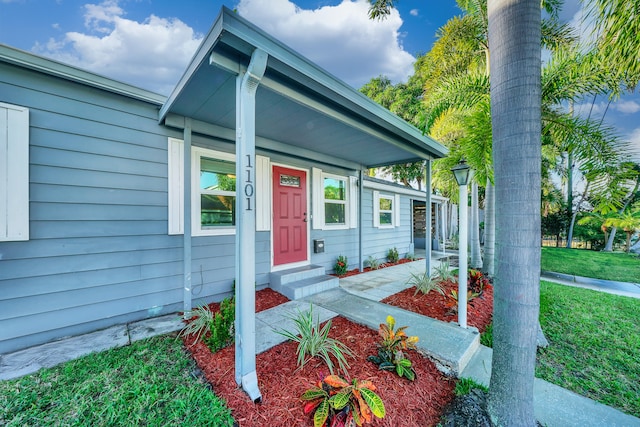 property entrance with covered porch and a lawn