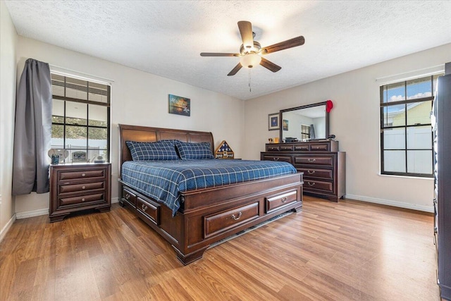 bedroom with multiple windows, a textured ceiling, light wood-type flooring, and ceiling fan