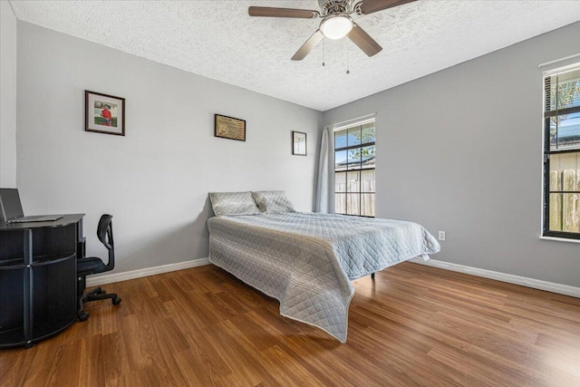 bedroom featuring multiple windows, wood-type flooring, and ceiling fan