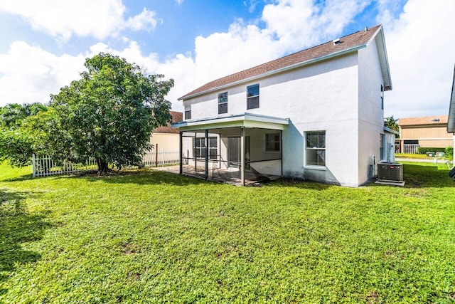 back of house with central air condition unit, a sunroom, and a lawn