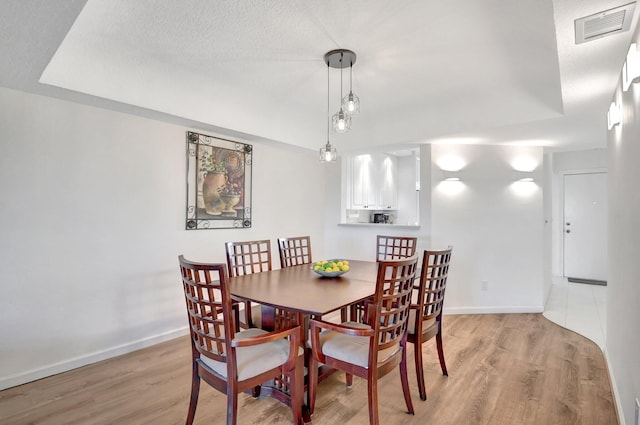dining area with light hardwood / wood-style floors and a textured ceiling