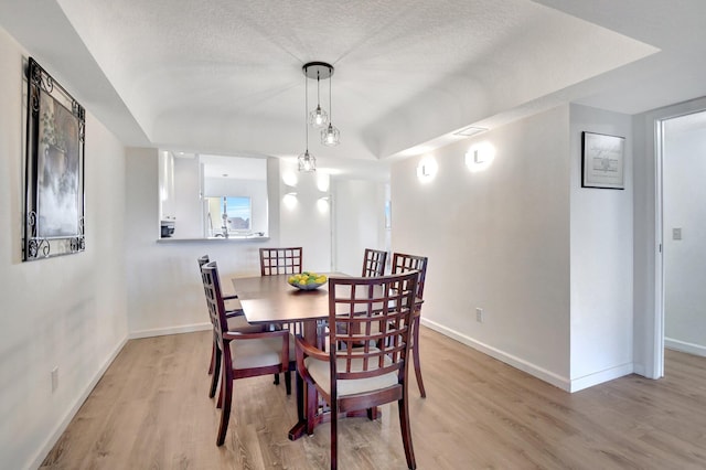dining room featuring light hardwood / wood-style flooring and a textured ceiling