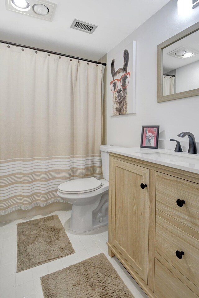 bathroom featuring walk in shower, vanity, toilet, and tile patterned flooring