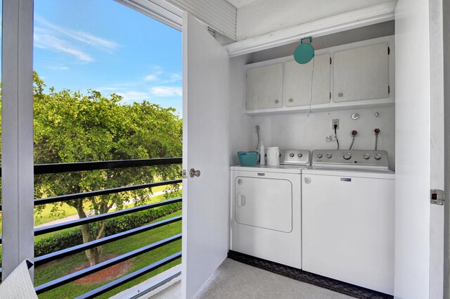 clothes washing area with cabinets, washer and dryer, and plenty of natural light