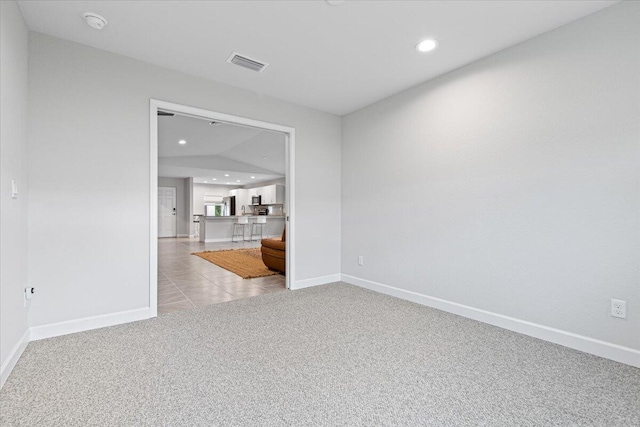 carpeted spare room with lofted ceiling