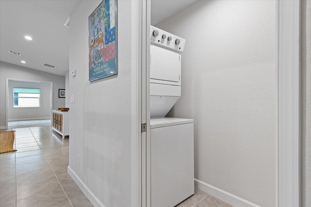 laundry room featuring stacked washing maching and dryer and light tile patterned floors