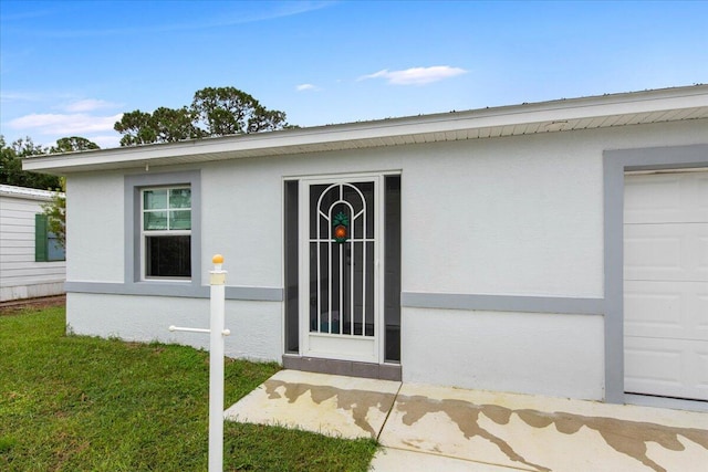 property entrance featuring a garage and a lawn