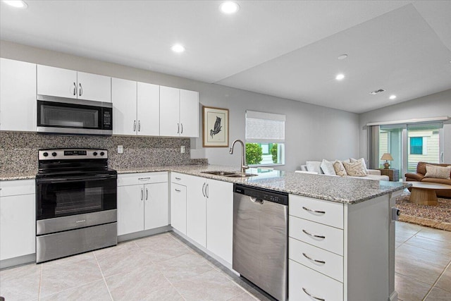 kitchen featuring tasteful backsplash, kitchen peninsula, stainless steel appliances, vaulted ceiling, and white cabinets