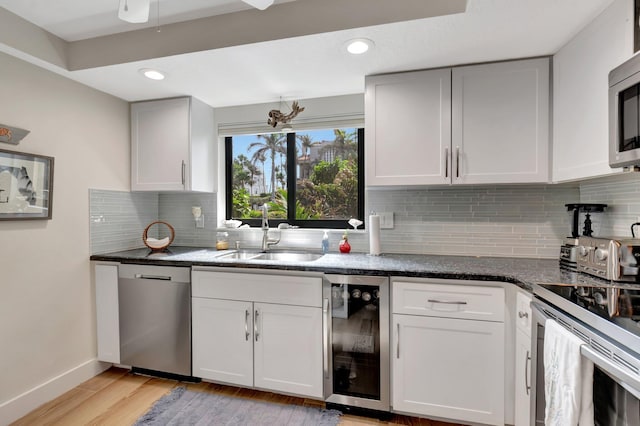 kitchen featuring sink, white cabinetry, stainless steel appliances, and beverage cooler