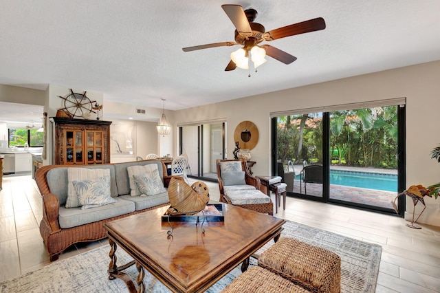 living room with a textured ceiling, light wood-type flooring, and ceiling fan