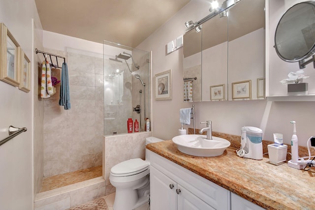 bathroom with vanity, toilet, tile patterned floors, and tiled shower