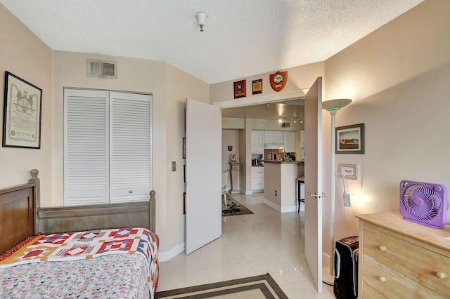 bedroom with a closet, a textured ceiling, and light tile patterned floors