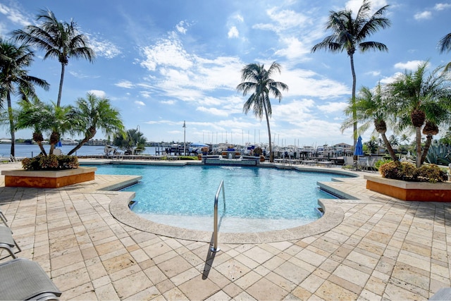 view of pool featuring a patio and a water view