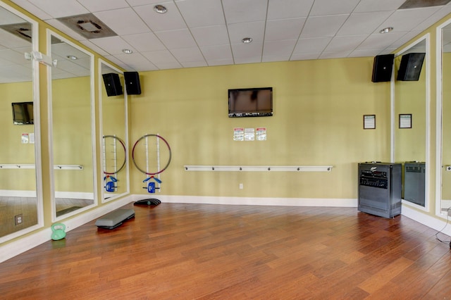 exercise room featuring wood-type flooring and a drop ceiling