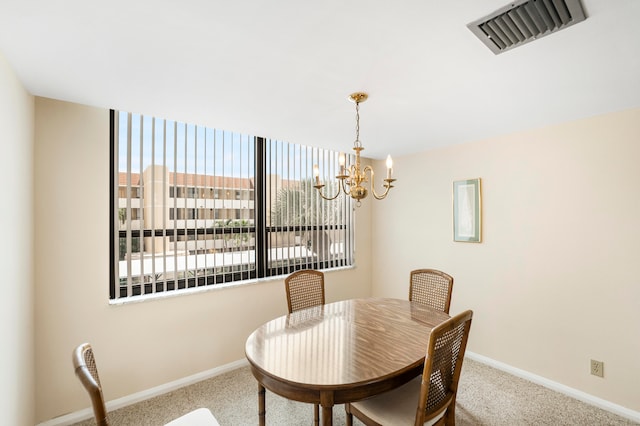 carpeted dining area with a chandelier