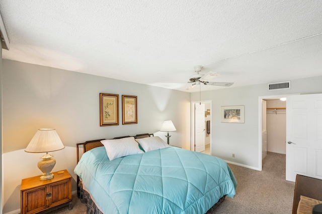 bedroom featuring a closet, ceiling fan, carpet, and a walk in closet