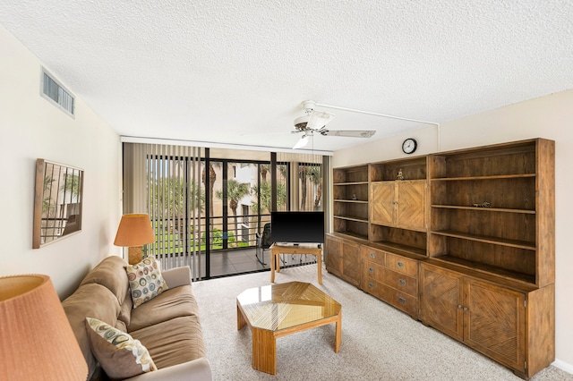 living room featuring light carpet, a textured ceiling, and ceiling fan