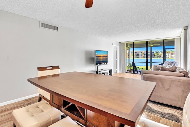 interior space with ceiling fan, a textured ceiling, light hardwood / wood-style flooring, and floor to ceiling windows