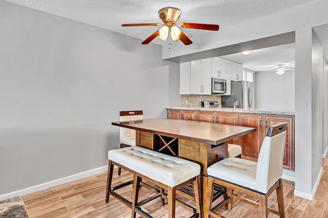 dining room featuring light hardwood / wood-style floors, a textured ceiling, sink, and ceiling fan