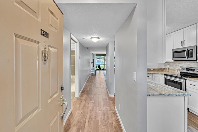 hall featuring light hardwood / wood-style floors and a textured ceiling