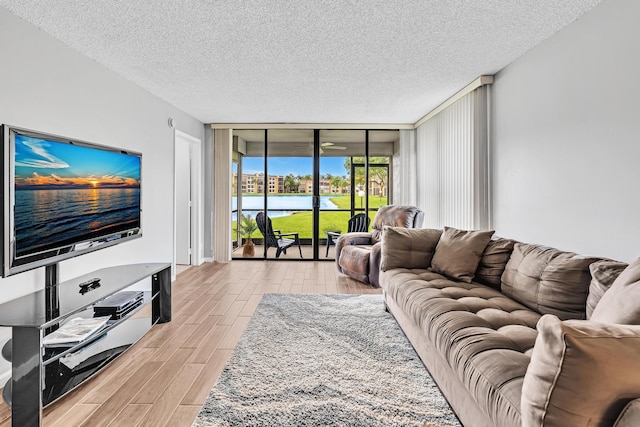 living room featuring a wall of windows, a textured ceiling, and light wood-type flooring