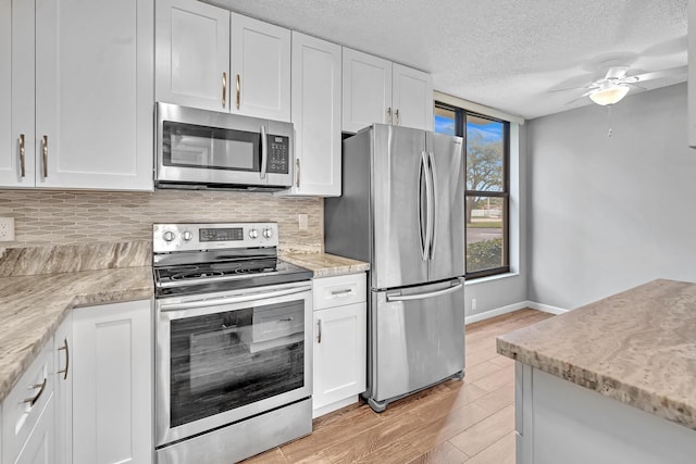 kitchen featuring appliances with stainless steel finishes, white cabinetry, backsplash, and light hardwood / wood-style floors