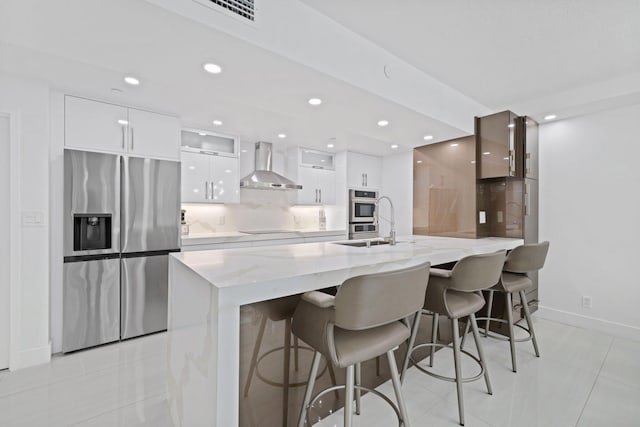 kitchen featuring stainless steel fridge, wall chimney exhaust hood, modern cabinets, white cabinetry, and backsplash