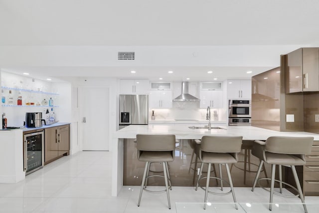 kitchen with stainless steel appliances, a sink, modern cabinets, beverage cooler, and wall chimney exhaust hood