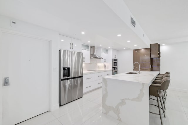 kitchen with white cabinets, wall chimney exhaust hood, modern cabinets, stainless steel appliances, and a sink