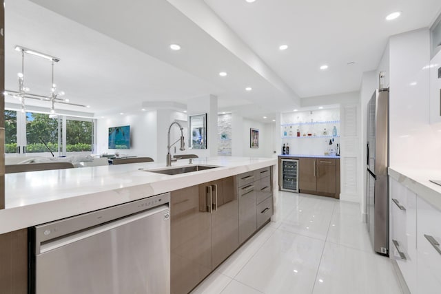 kitchen with beverage cooler, a sink, open floor plan, appliances with stainless steel finishes, and modern cabinets