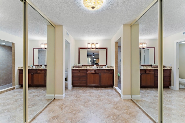 bathroom with vanity, toilet, and a textured ceiling