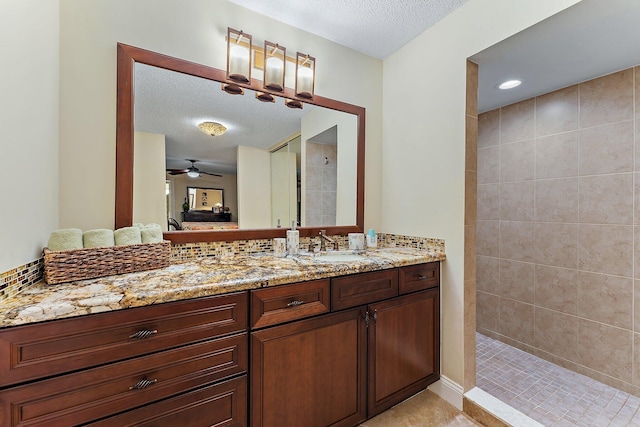 bathroom featuring vanity, ceiling fan, a textured ceiling, and tiled shower