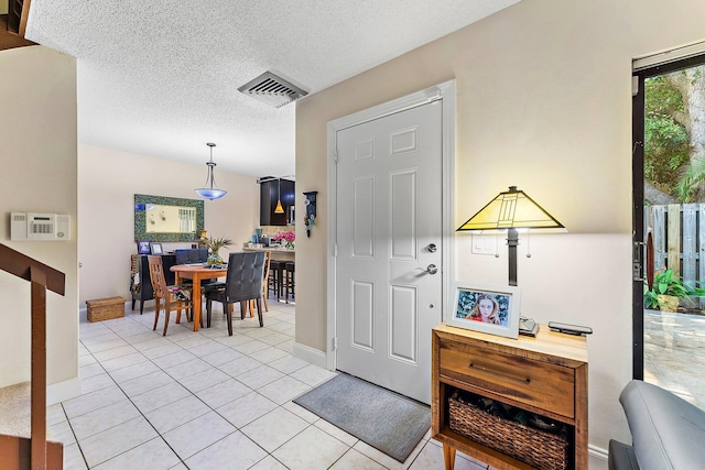 tiled entryway with a textured ceiling