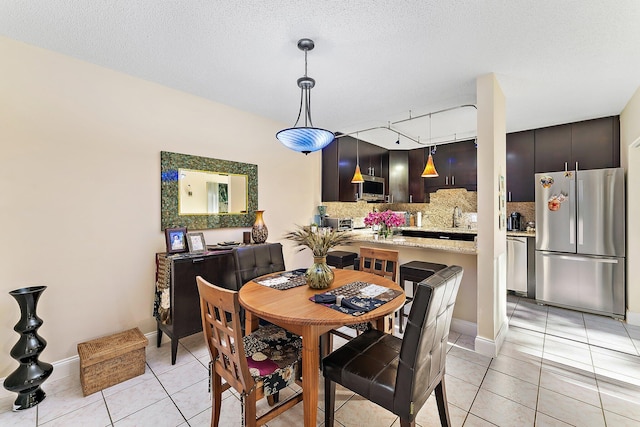 tiled dining space with a textured ceiling, track lighting, and sink