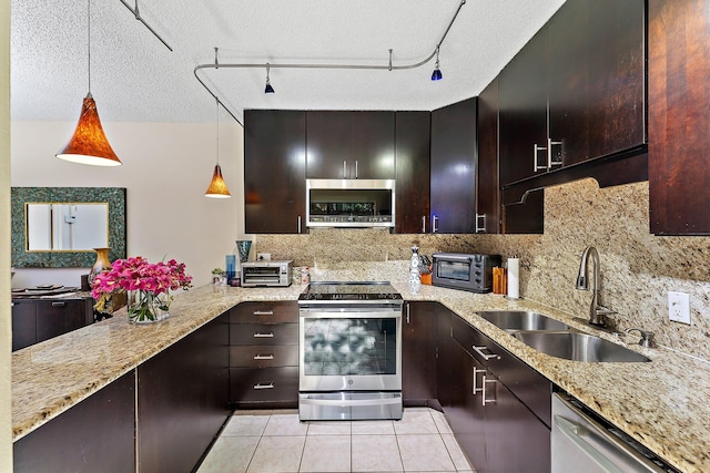 kitchen with sink, pendant lighting, light tile patterned floors, appliances with stainless steel finishes, and a textured ceiling