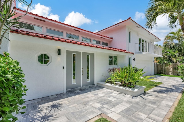 view of front of home featuring a garage, a balcony, and french doors