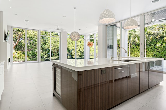 kitchen with hanging light fixtures, a wealth of natural light, sink, and a large island with sink