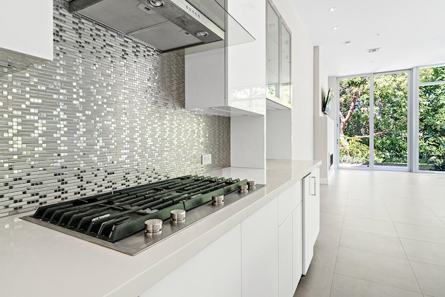 kitchen featuring a wealth of natural light, backsplash, white cabinets, and stainless steel gas stovetop