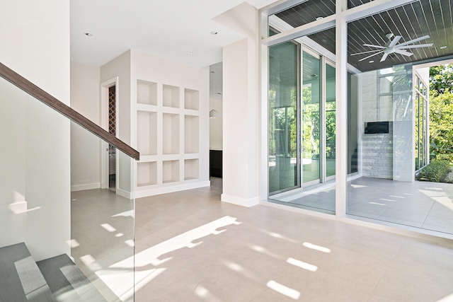 empty room with a wall of windows, ceiling fan, and plenty of natural light