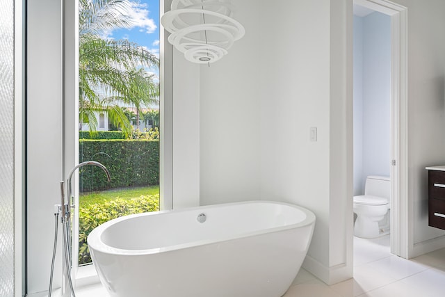 bathroom featuring tile patterned flooring, vanity, a notable chandelier, toilet, and a bathtub