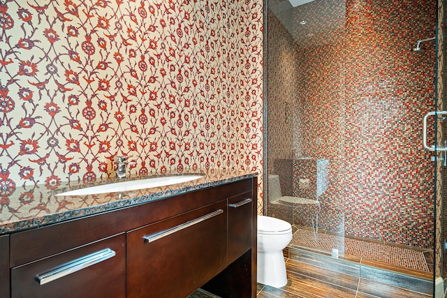 bathroom with toilet, vanity, a shower with door, and tile walls