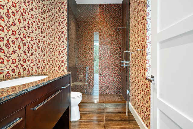 bathroom featuring toilet, vanity, and a shower with door