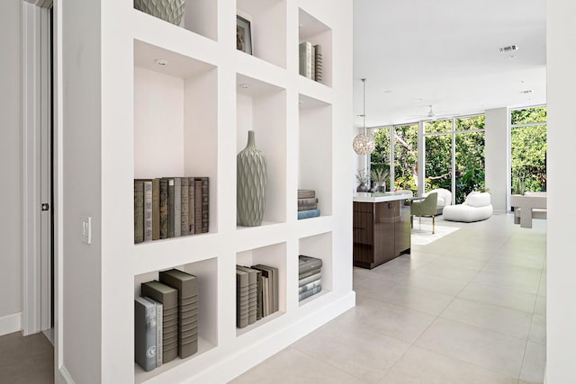 hallway featuring built in features, a wall of windows, and light tile patterned floors