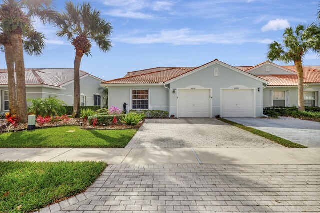 8503 Logia Cir, Boynton Beach, FL 33472 - view of front facade with a tile roof, a garage, stucco siding, a front lawn, and decorative driveway