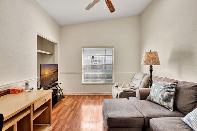 living room featuring ceiling fan, lofted ceiling, and light wood-type flooring