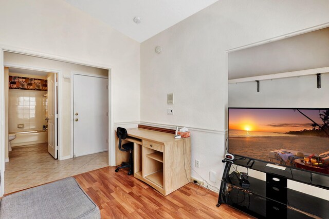 home office featuring vaulted ceiling and light hardwood / wood-style flooring