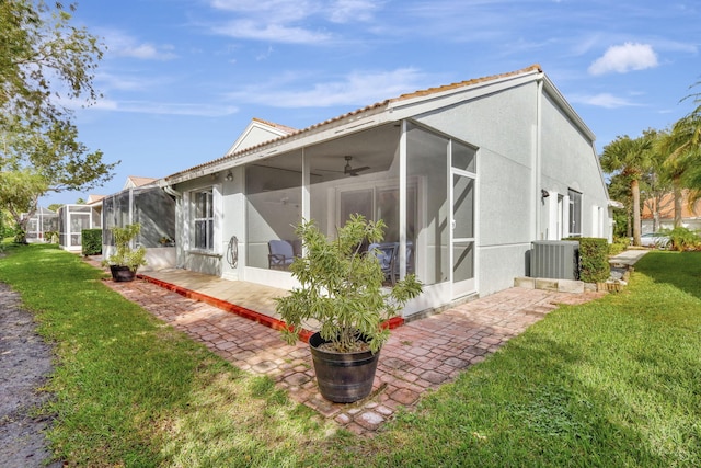 back of property featuring a yard, ceiling fan, and glass enclosure