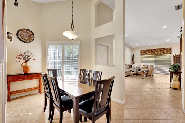 tiled dining space featuring a high ceiling and ceiling fan