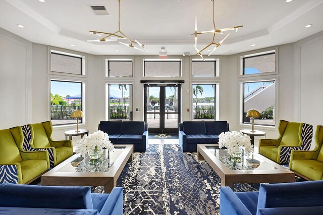 living room with crown molding, french doors, a notable chandelier, and a tray ceiling