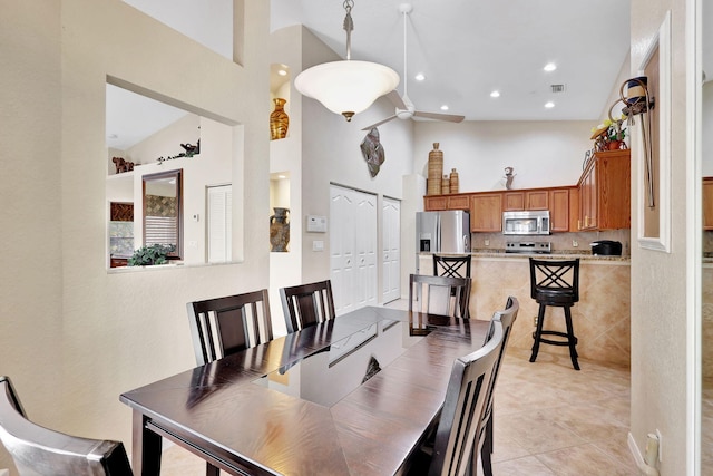 tiled dining area with high vaulted ceiling and ceiling fan